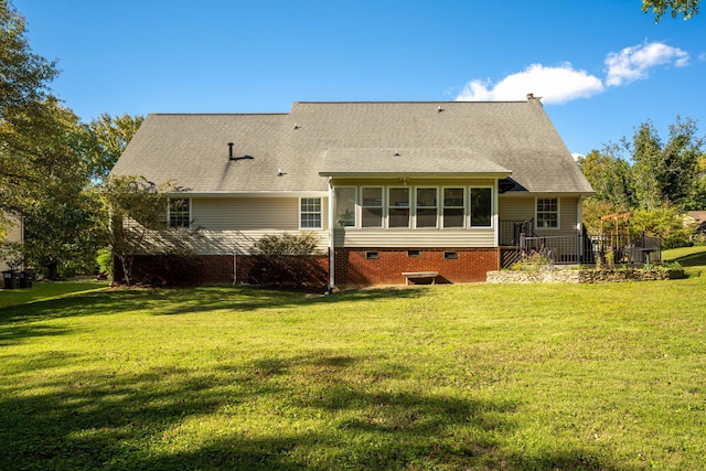 back of house featuring a sunroom, a lawn, and roof with shingles