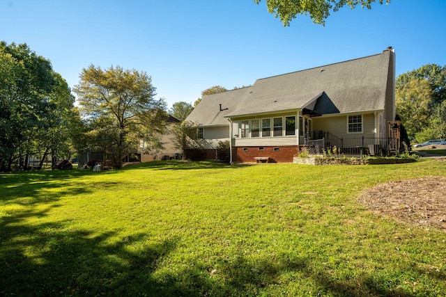 back of property featuring a lawn, a sunroom, and roof with shingles