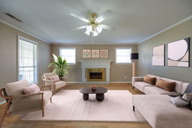 living area featuring visible vents, baseboards, ceiling fan, ornamental molding, and light wood-style flooring