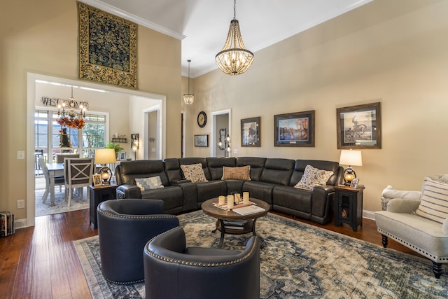 living room with an inviting chandelier, ornamental molding, a high ceiling, and dark hardwood / wood-style flooring