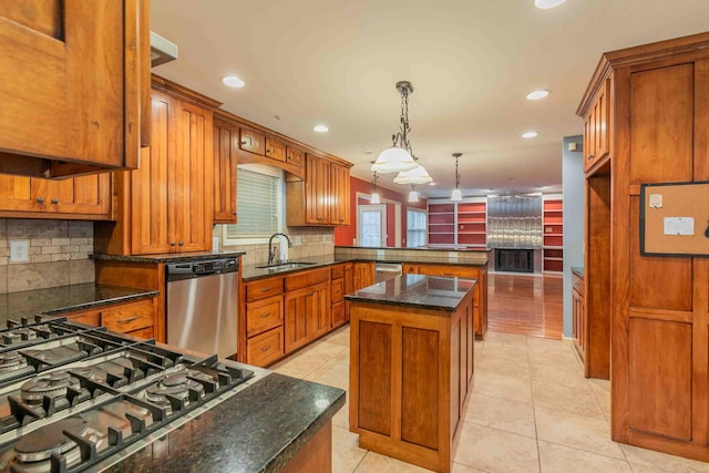 kitchen with brown cabinetry, tasteful backsplash, a sink, a peninsula, and stainless steel appliances