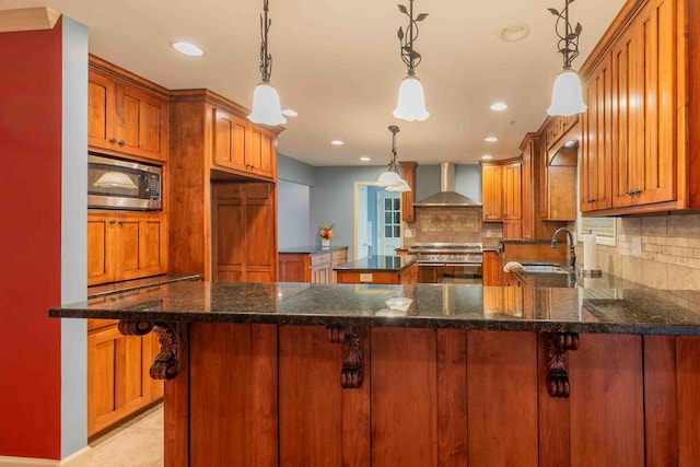 kitchen with wall chimney range hood, tasteful backsplash, sink, pendant lighting, and stainless steel appliances