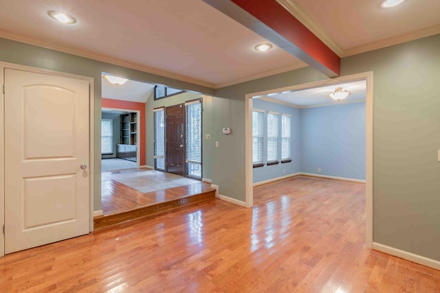 foyer entrance featuring light hardwood / wood-style flooring, ornamental molding, and beam ceiling