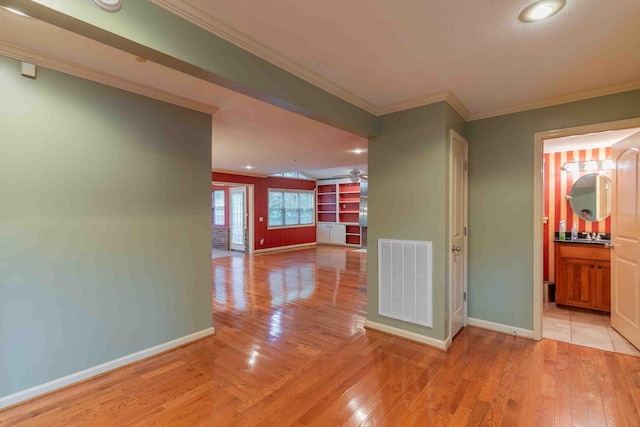 corridor with light hardwood / wood-style floors and crown molding