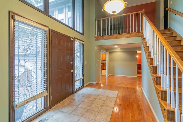 foyer entrance featuring a towering ceiling and light hardwood / wood-style flooring