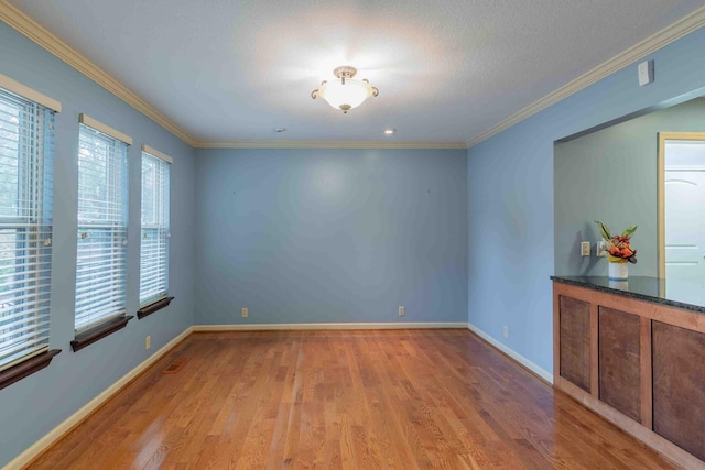 spare room featuring light hardwood / wood-style flooring, ornamental molding, and a textured ceiling