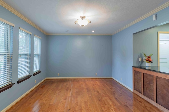 unfurnished room with baseboards, ornamental molding, and wood finished floors
