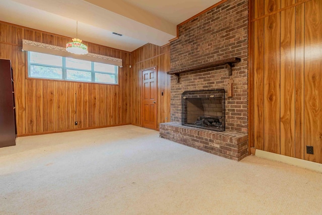 unfurnished living room featuring light colored carpet, wooden walls, and a fireplace