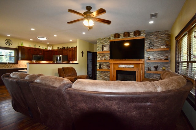 living room with ceiling fan, a fireplace, dark wood-type flooring, and a wealth of natural light