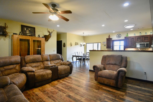 living room with ceiling fan with notable chandelier and dark hardwood / wood-style floors