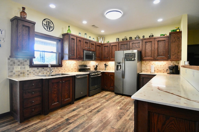 kitchen featuring sink, stainless steel appliances, light hardwood / wood-style floors, and decorative backsplash