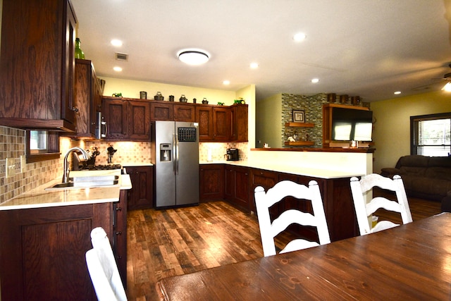 kitchen with ceiling fan, sink, dark hardwood / wood-style flooring, kitchen peninsula, and stainless steel fridge with ice dispenser