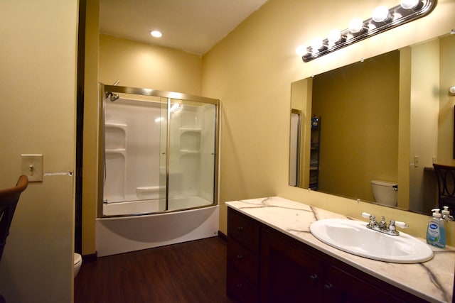 full bathroom with hardwood / wood-style floors, shower / bath combination with glass door, vanity, and toilet