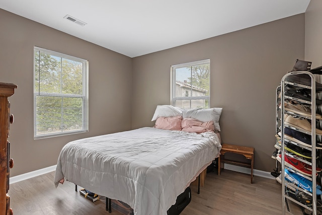 bedroom with multiple windows and light wood-type flooring