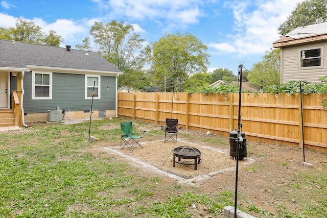 view of yard featuring central air condition unit and a fire pit