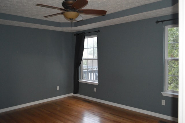 unfurnished room with ceiling fan, hardwood / wood-style flooring, a textured ceiling, and plenty of natural light