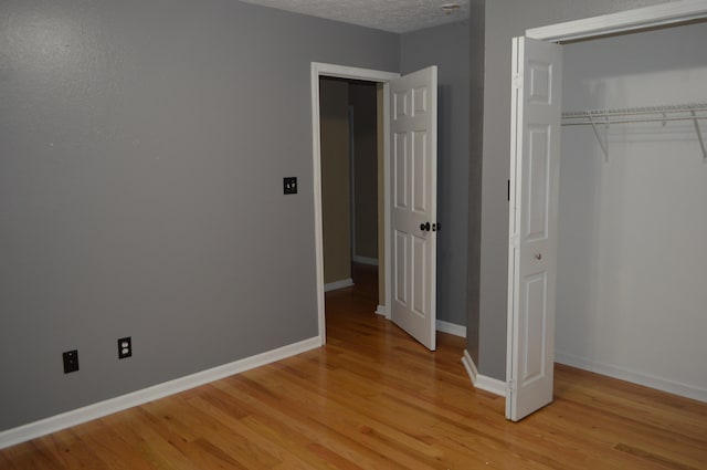 unfurnished bedroom with light hardwood / wood-style floors, a closet, and a textured ceiling