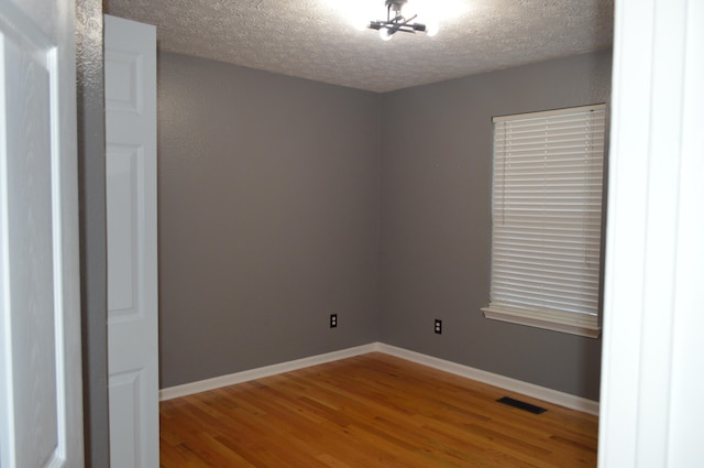 unfurnished room featuring a textured ceiling and hardwood / wood-style floors