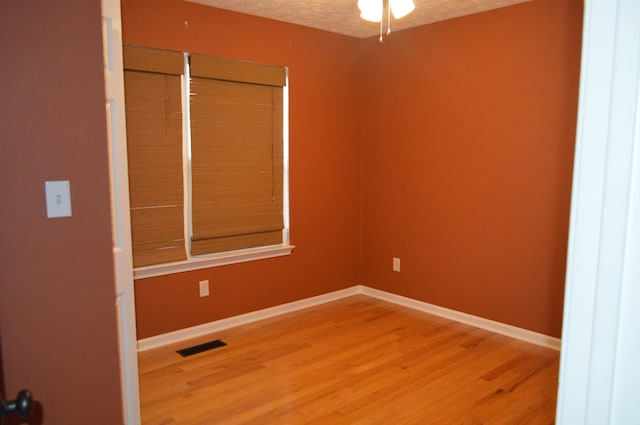 unfurnished room with a textured ceiling, wood-type flooring, and ceiling fan