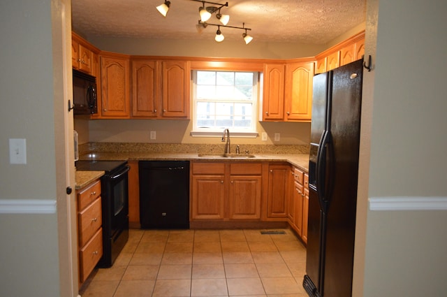 kitchen with sink, black appliances, light stone countertops, light tile patterned floors, and a textured ceiling