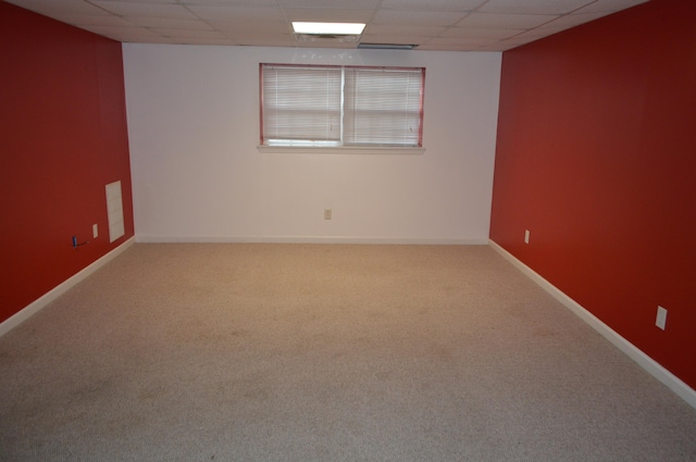 spare room featuring carpet flooring and a drop ceiling