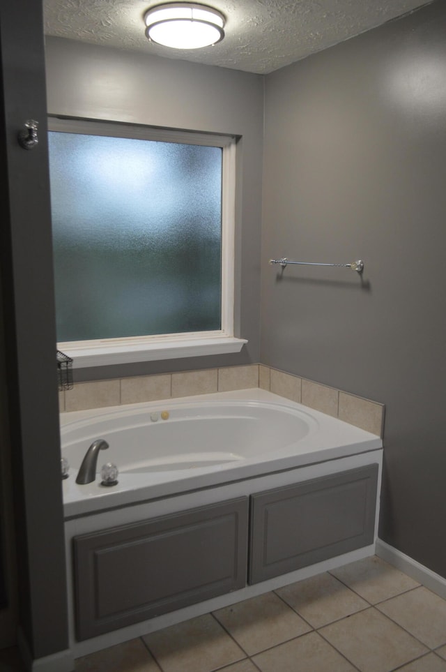 bathroom with a textured ceiling, tile patterned flooring, and a bathing tub