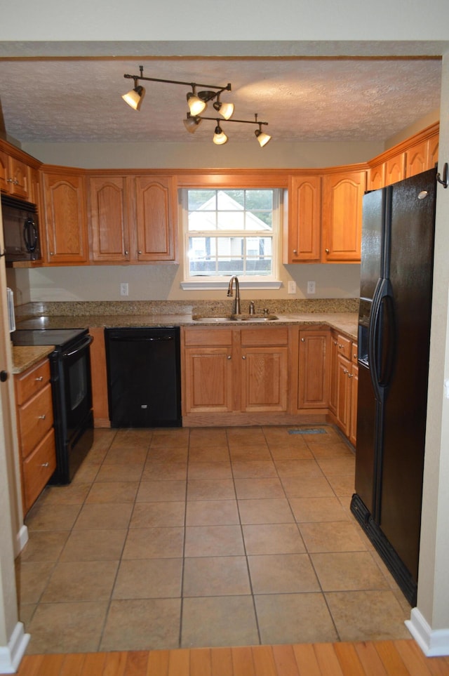 kitchen with a textured ceiling, black appliances, sink, and light tile patterned floors