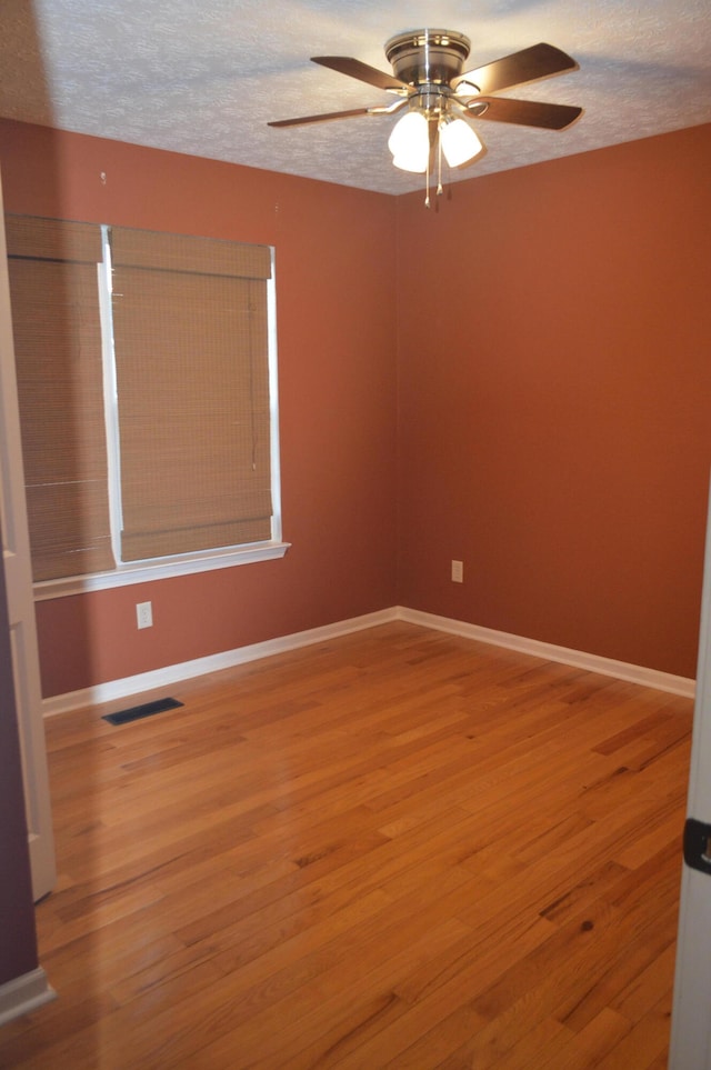 spare room featuring a textured ceiling, wood-type flooring, and ceiling fan