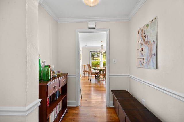 corridor with crown molding, a notable chandelier, and wood-type flooring