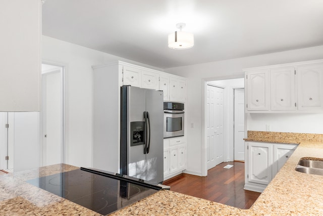 kitchen featuring appliances with stainless steel finishes, white cabinetry, light stone counters, and dark hardwood / wood-style flooring