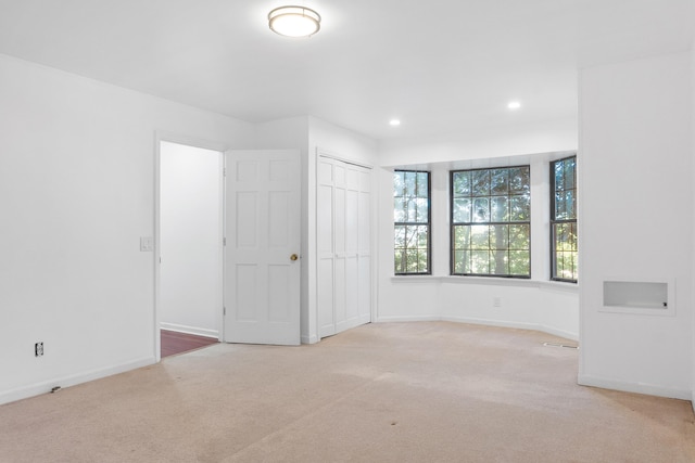 unfurnished bedroom featuring a closet and light colored carpet