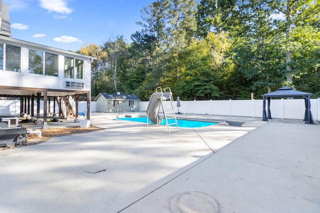 view of swimming pool with a patio area, a water slide, a gazebo, and a storage unit