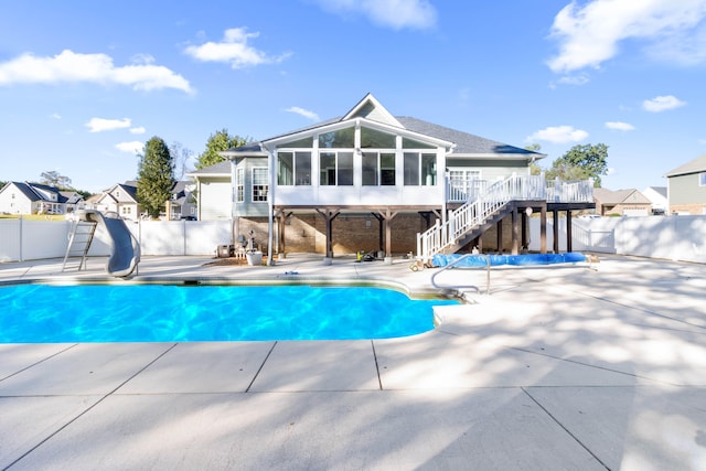 view of swimming pool featuring a patio area, a sunroom, and a water slide