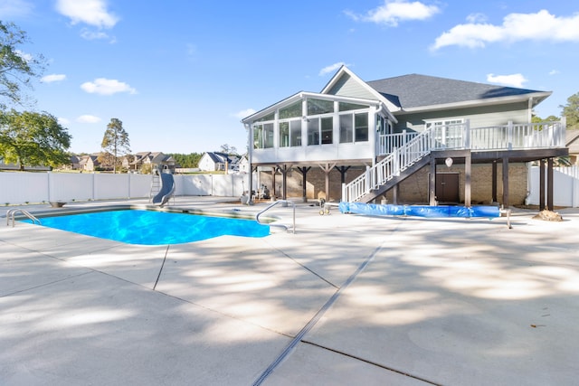 view of swimming pool with a patio area, a water slide, and a sunroom