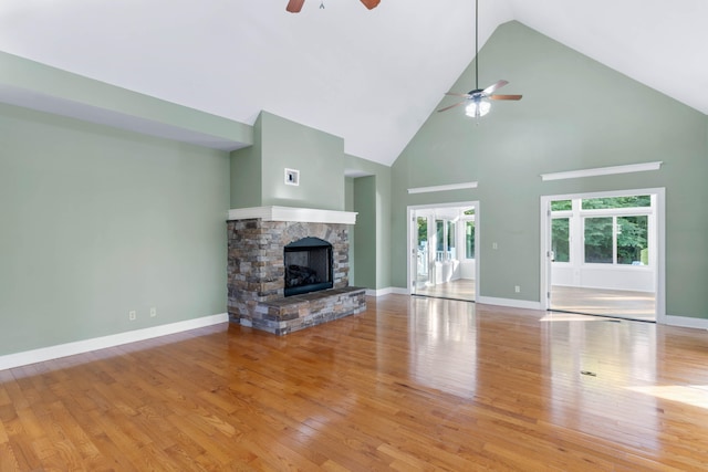 unfurnished living room with ceiling fan, high vaulted ceiling, light hardwood / wood-style flooring, and a fireplace