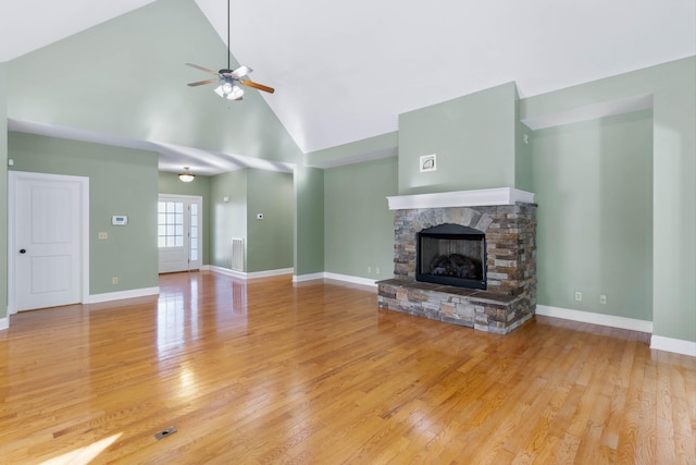 unfurnished living room with a fireplace, high vaulted ceiling, light wood-type flooring, and ceiling fan