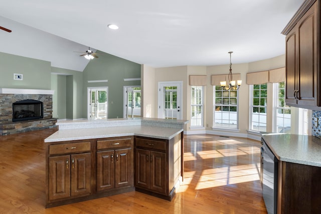 kitchen with a fireplace, vaulted ceiling, light wood-type flooring, and a kitchen island