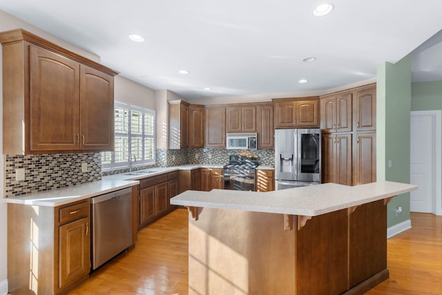 kitchen featuring sink, a kitchen bar, light hardwood / wood-style floors, stainless steel appliances, and decorative backsplash