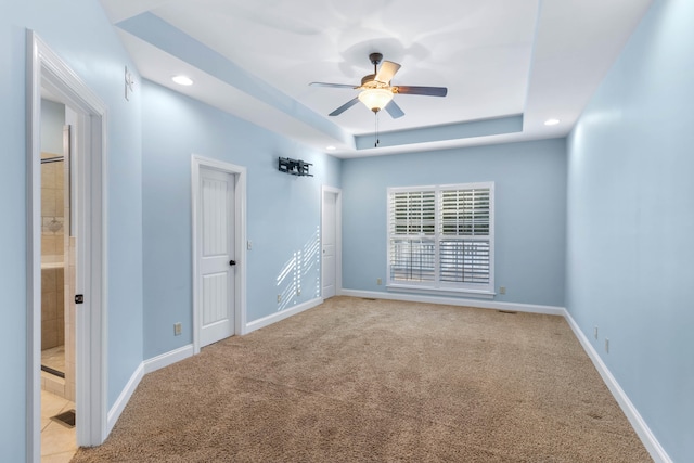 carpeted empty room featuring ceiling fan and a tray ceiling