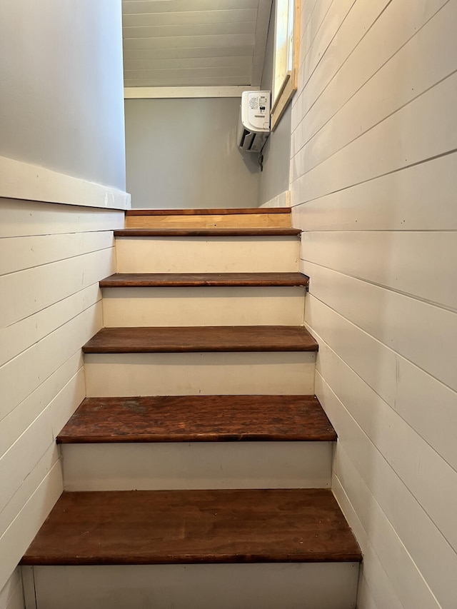 stairway featuring wood walls