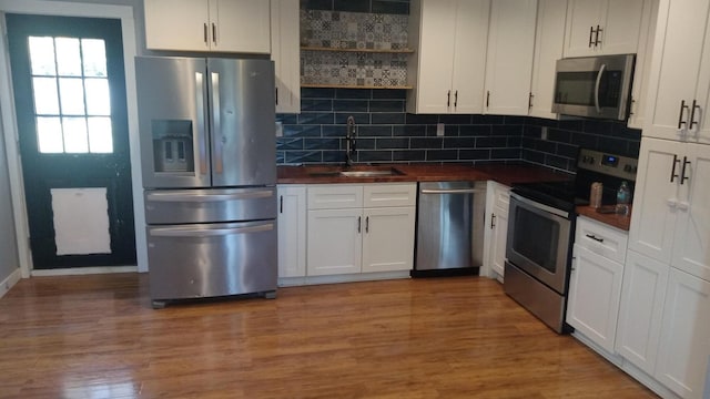 kitchen with hardwood / wood-style floors, sink, decorative backsplash, appliances with stainless steel finishes, and white cabinetry