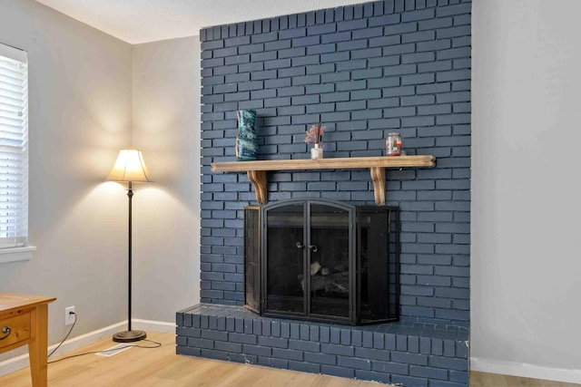 room details with a brick fireplace, hardwood / wood-style flooring, and a textured ceiling