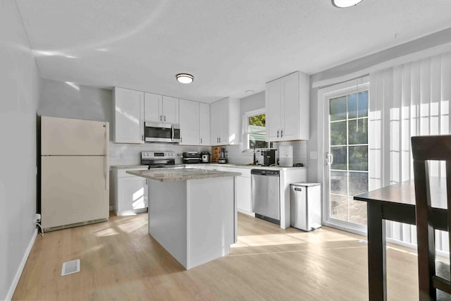 kitchen featuring appliances with stainless steel finishes, a center island, decorative backsplash, and white cabinetry