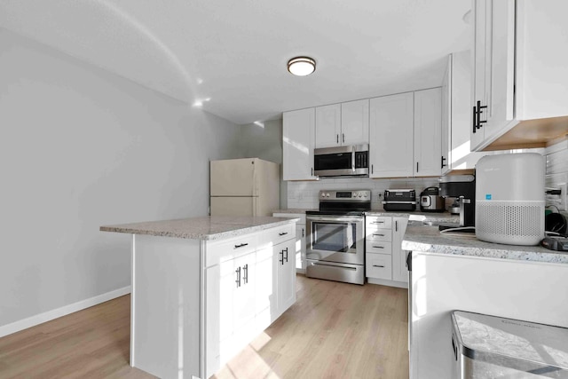 kitchen featuring tasteful backsplash, light hardwood / wood-style flooring, stainless steel appliances, a center island, and white cabinetry