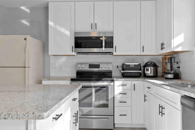 kitchen with white cabinets, appliances with stainless steel finishes, and backsplash