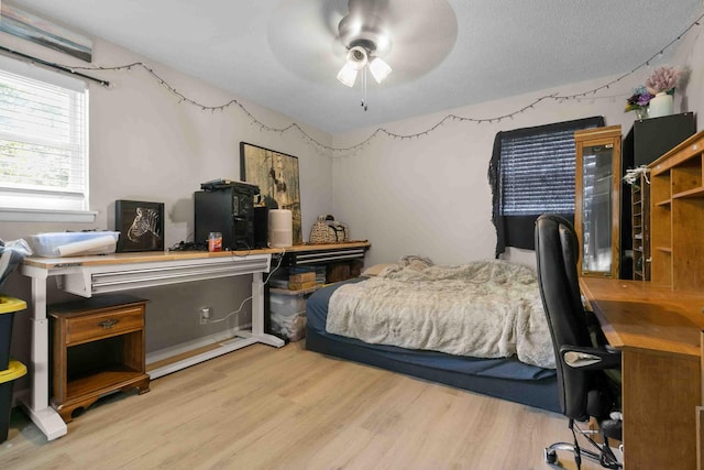 bedroom with a textured ceiling, light wood-type flooring, and ceiling fan