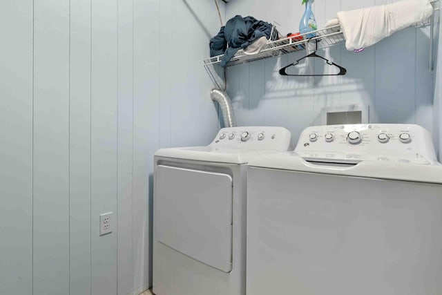 laundry room with wood walls and washing machine and clothes dryer