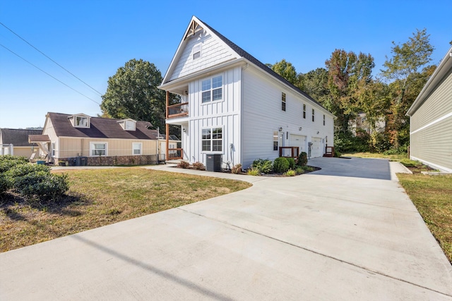 view of front of house featuring a front lawn, central air condition unit, a garage, and a balcony