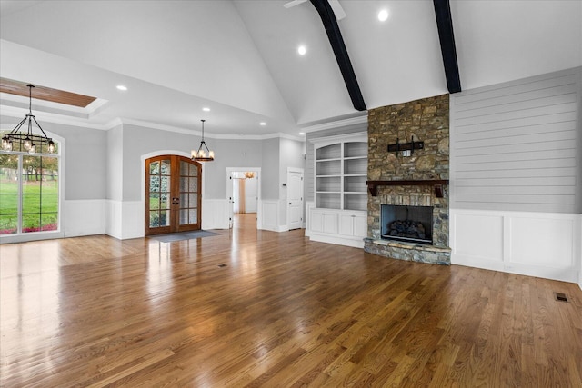 unfurnished living room with ornamental molding, wood-type flooring, a fireplace, and french doors