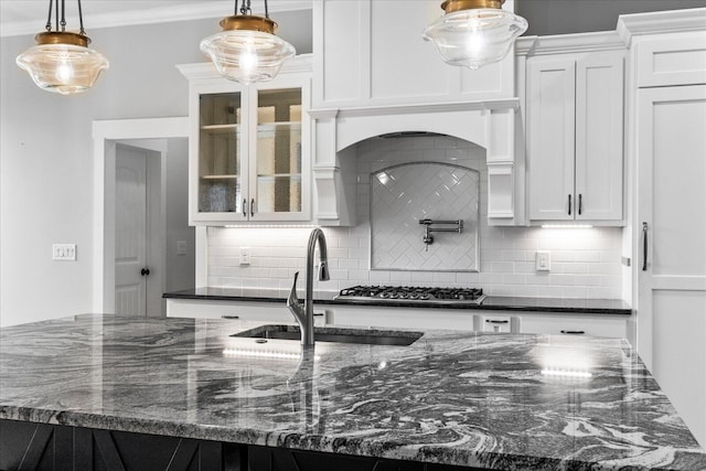 kitchen with backsplash, white cabinetry, hanging light fixtures, and dark stone countertops